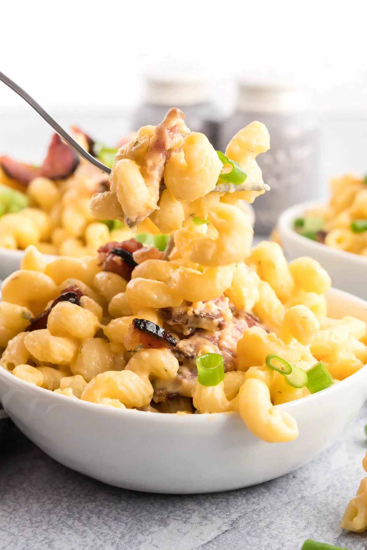 Bowl of bacon Mac and cheese with a bite on a fork. 