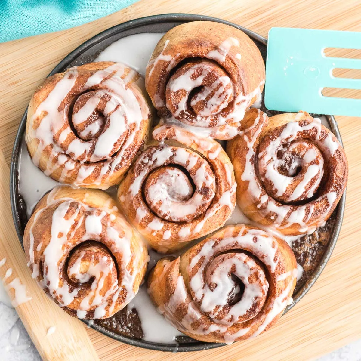 Cinnamon rolls drizzled with icing on a plate.