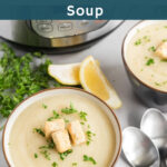 Cauliflower soup in a bowl garnished with croutons and chopped parsley with lemon wedge on the side.