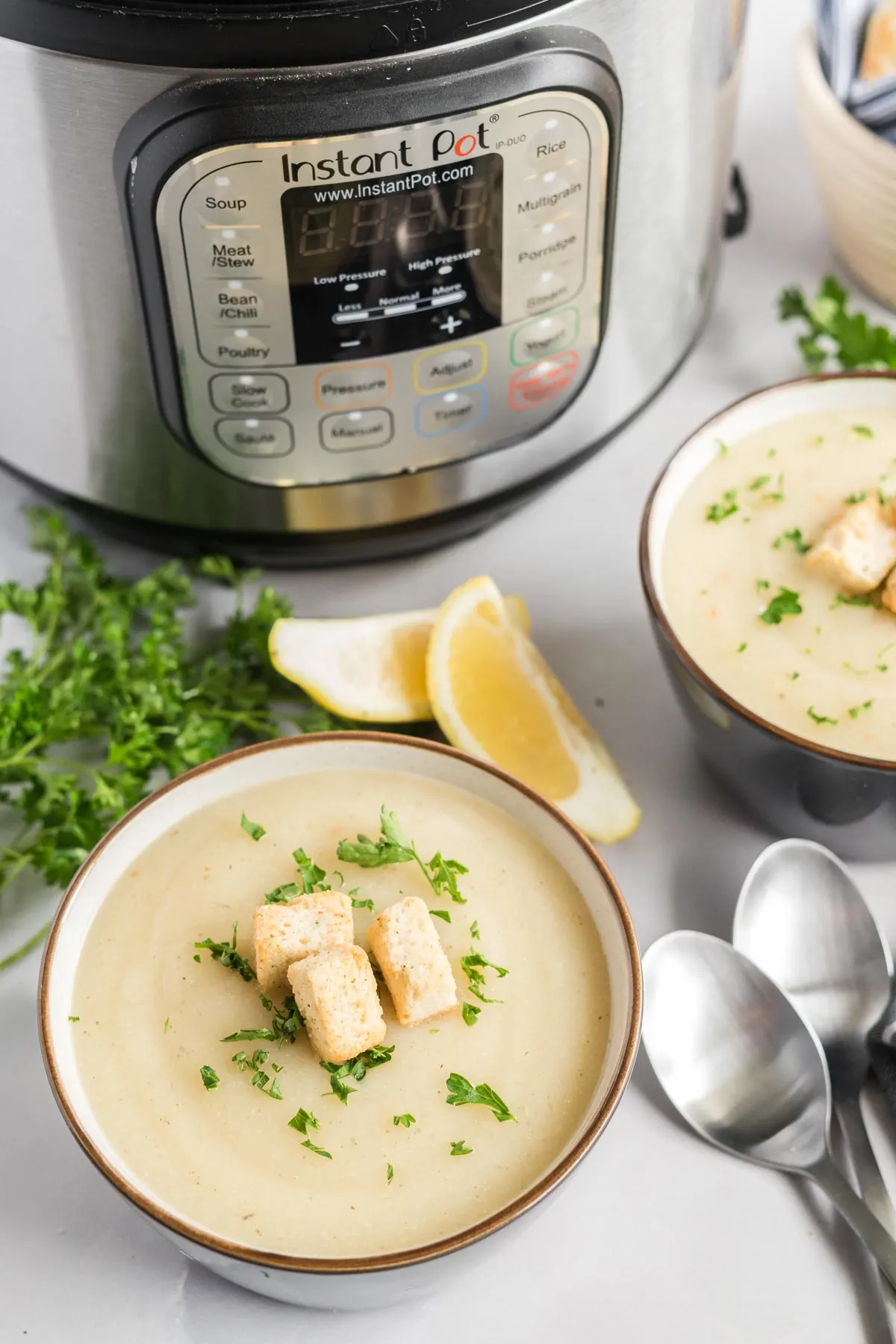 Cauliflower soup in bowls beside an instant pot. 