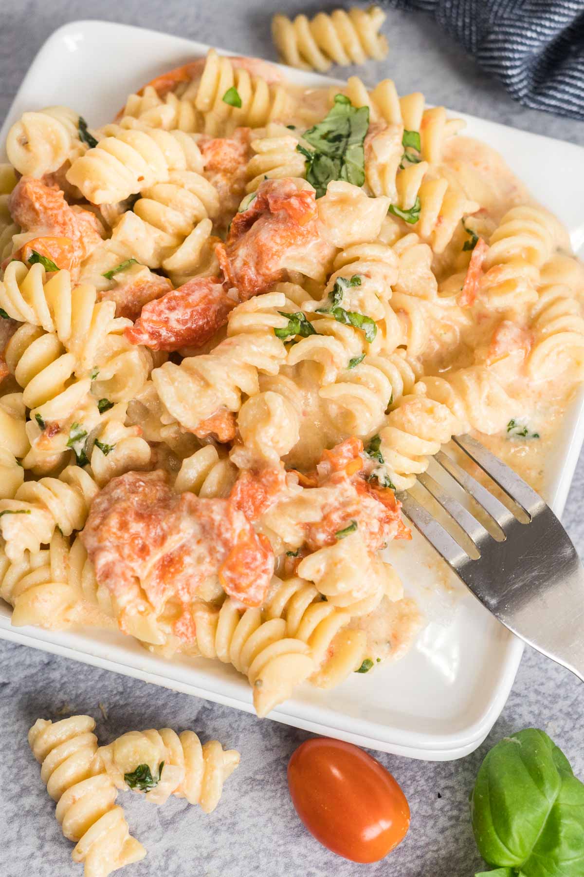 Tomato feta pasta on a white plate with a fork.
