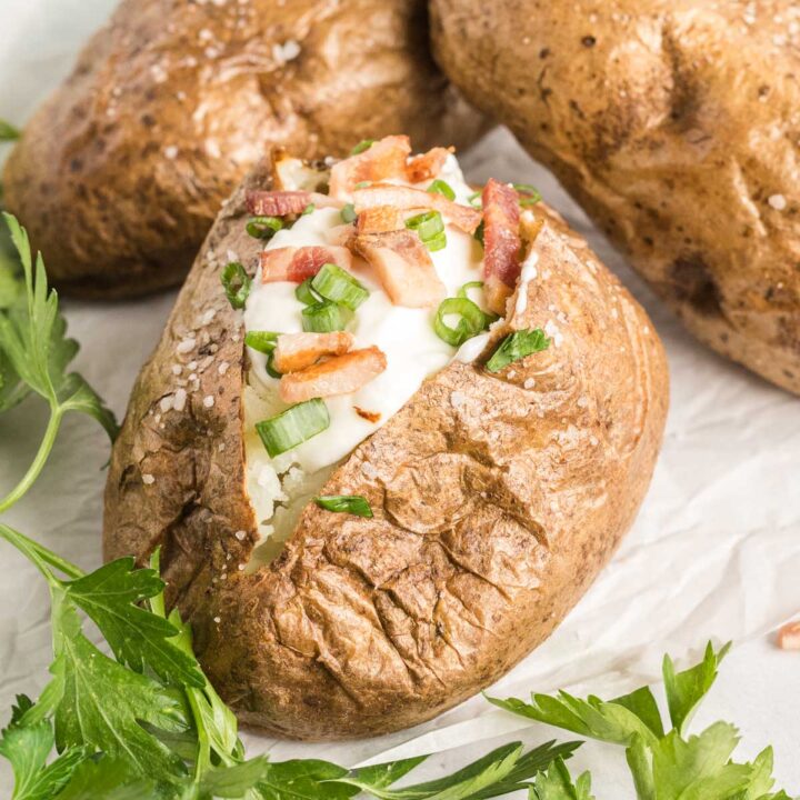 Baked potato split open and filled with sour cream, green onion and diced bacon.
