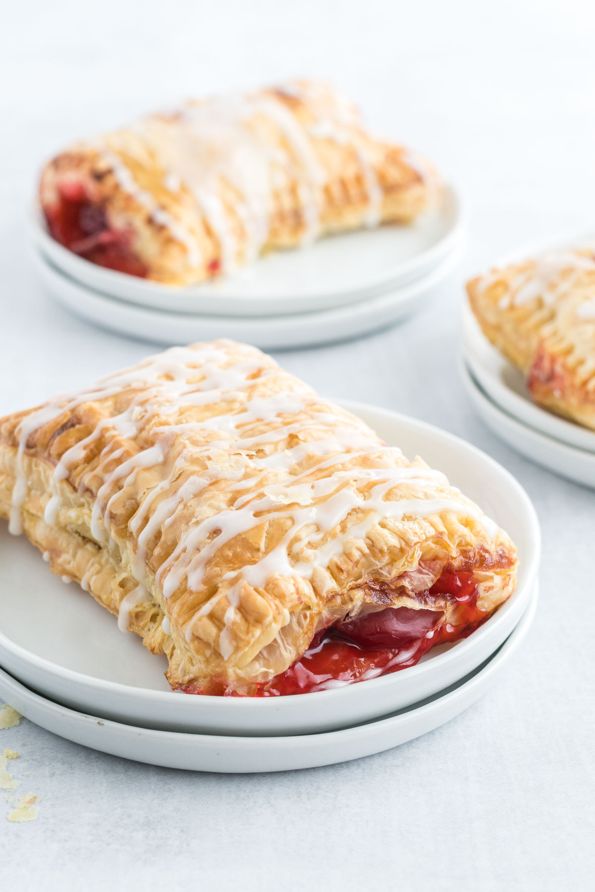 A cherry turnover with icing drizzle on a small plate.