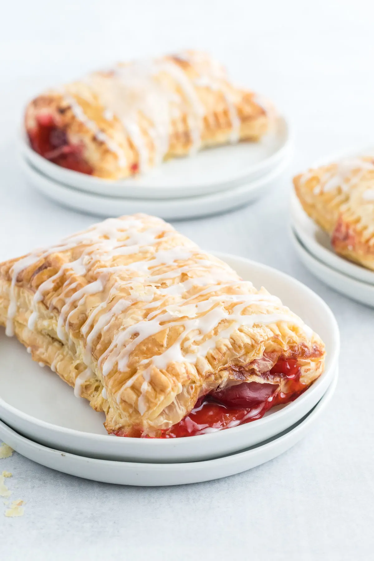 A cherry turnover with icing drizzle on a small plate.