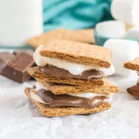 Two smores with melted chocolate and marshmallow stacked on top of each other.