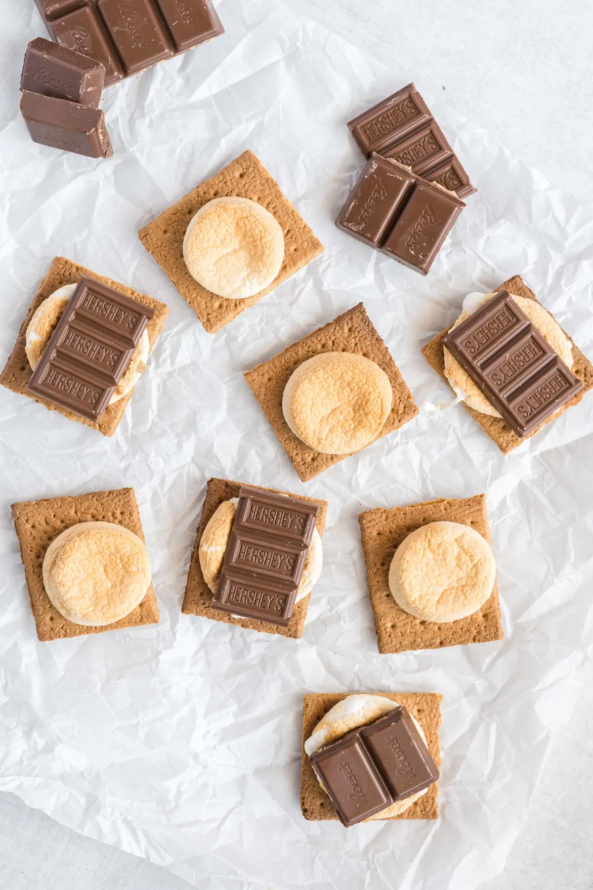 Graham cracker halves with toasted marshmallows and chocolate squares on half of them.