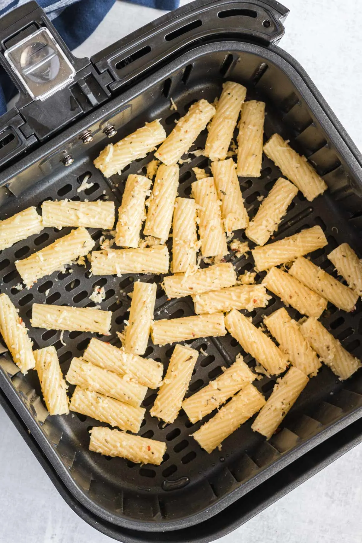 Seasoned pasta in an air fryer basket.