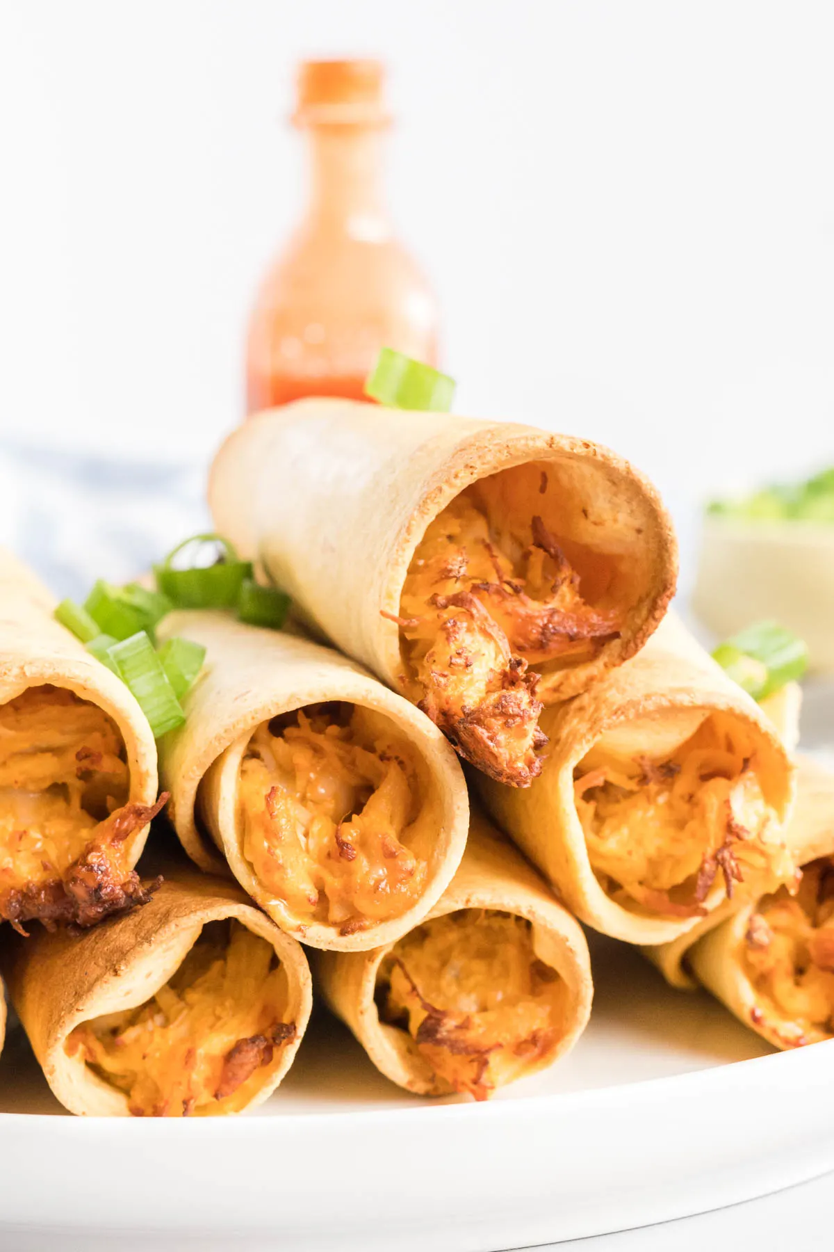 A stack of chicken taquitos on a plate. 