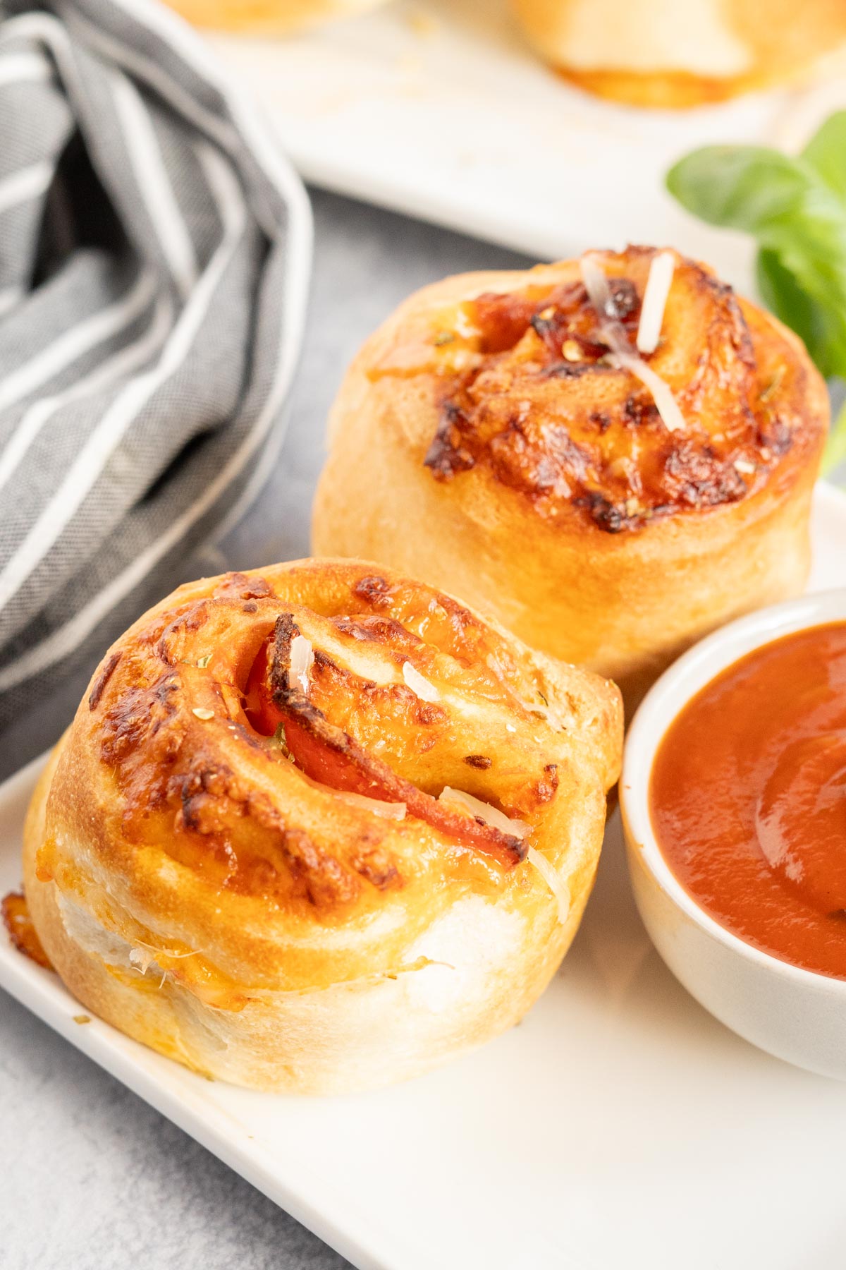 Two pizza rolls with a dish of pizza sauce.