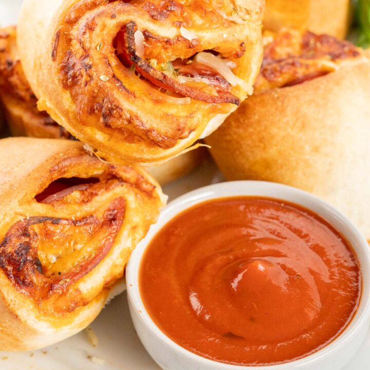 Pizza Rolls on a plate with a bowl of pizza sauce for dipping.