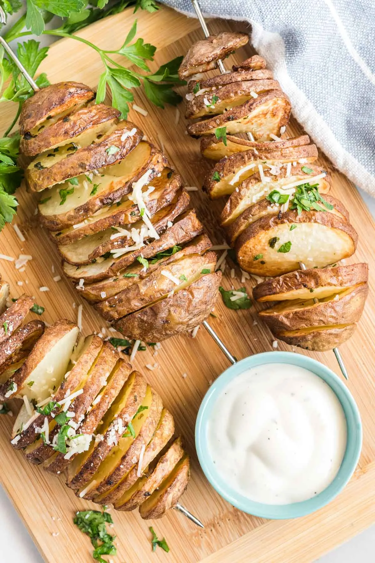 Crispy spiralled potatoes on a cutting board with chopped fresh herbs and ranch dip.