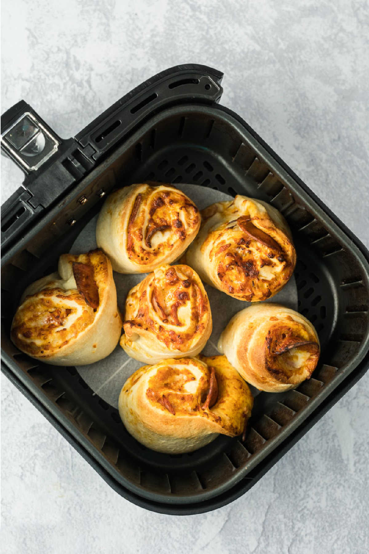 Six baked pizza rolls that have risen and are golden brown.