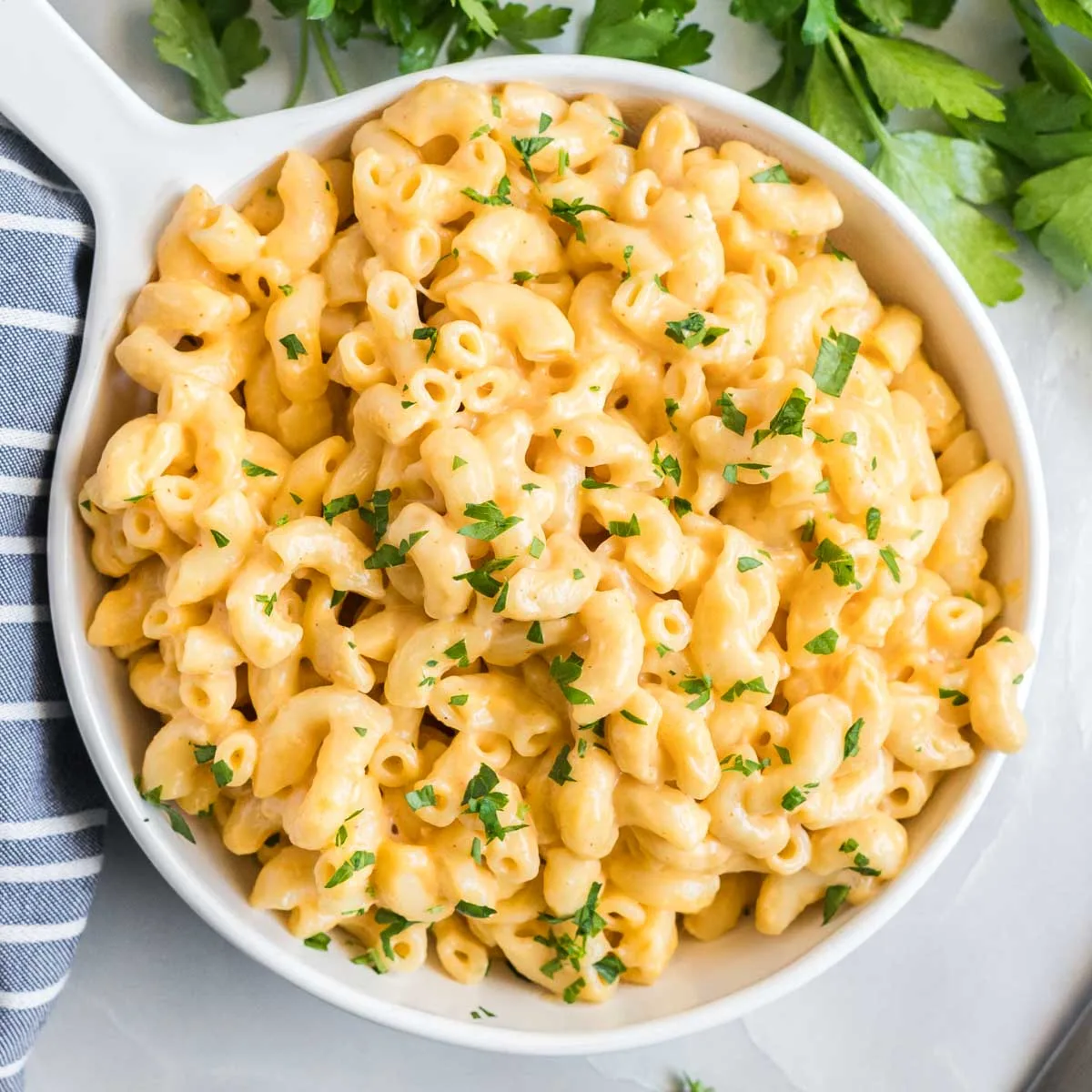 Dish of macaroni and cheese garnished with chopped parsley.