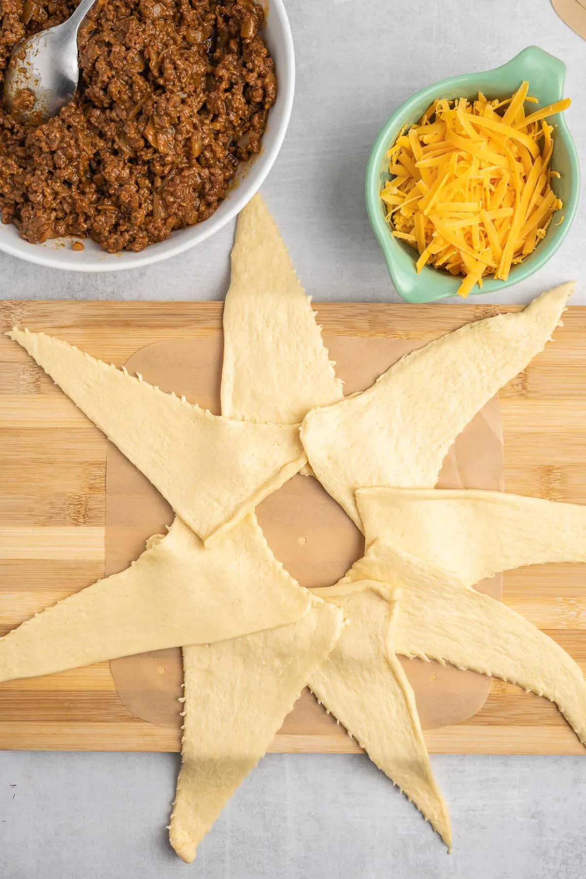 Eight crescent dough triangles arranged on a cutting board to look like a star. 