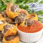 Meatball skewer dipped in a dish of pizza sauce.