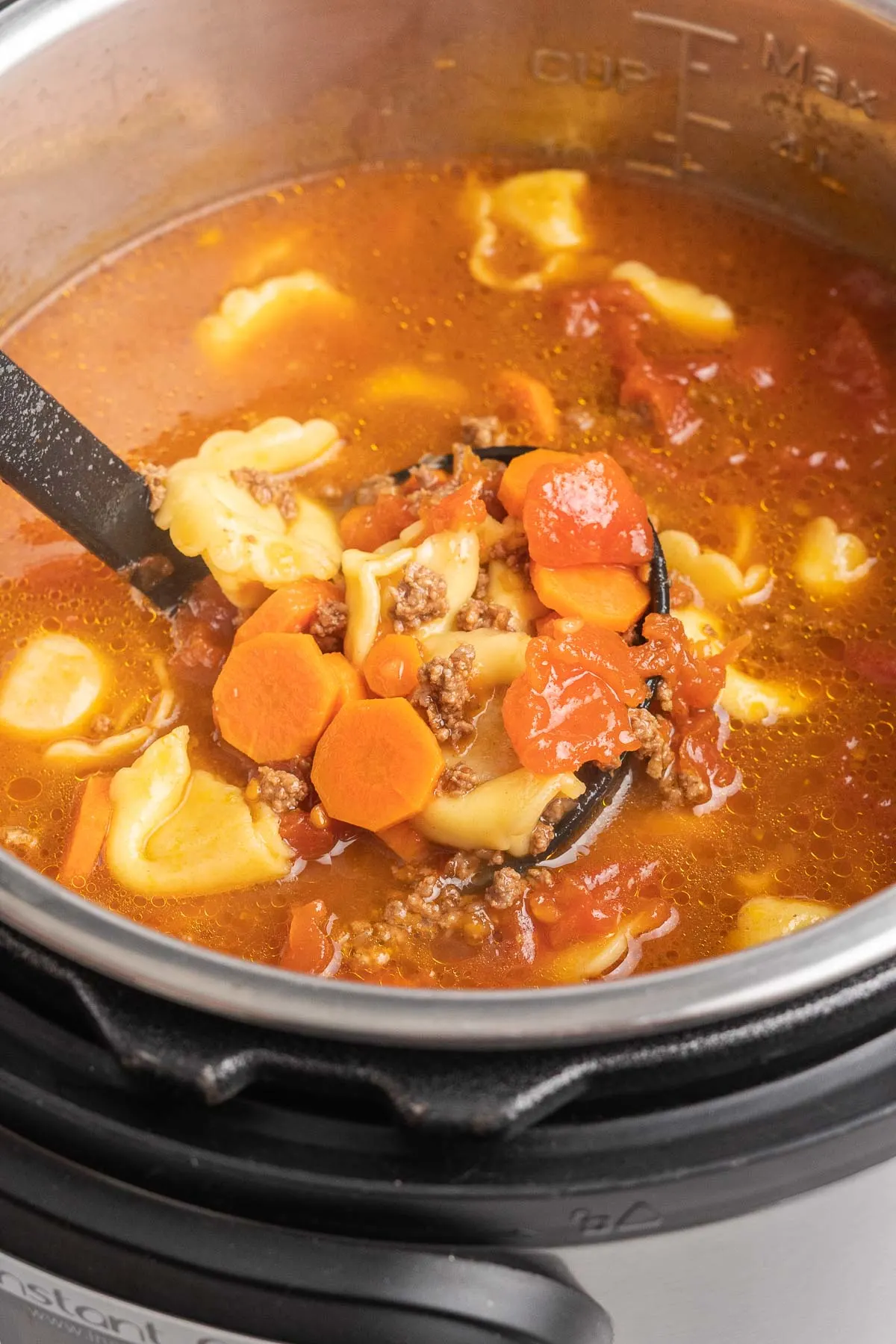 Ladle of tortellini soup in an instant pot. 