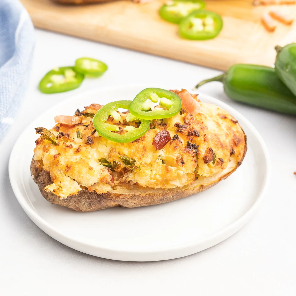 Stuffed potato topped with jalapeño slices on a small plate.