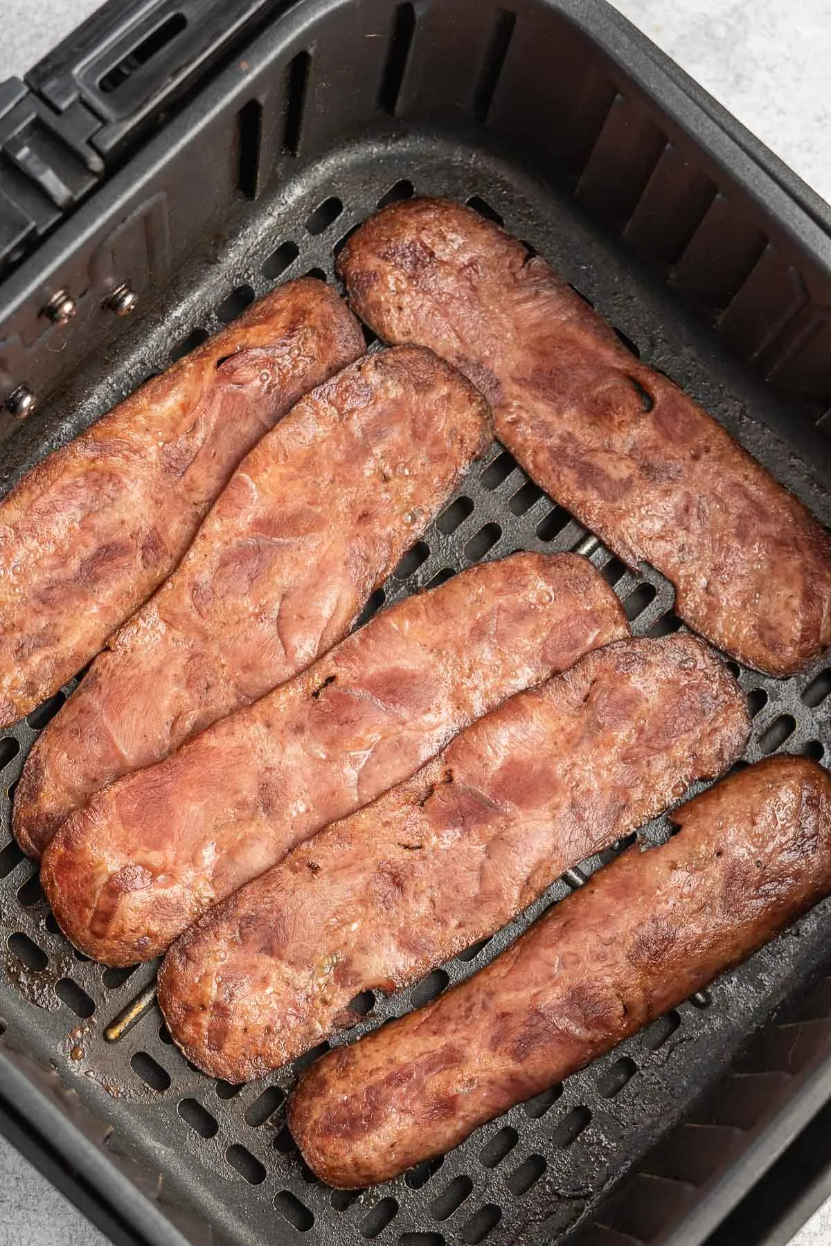 Crispy cooked turkey bacon in an air fryer basket.