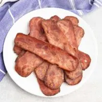 Slices of cooked turkey bacon on a white plate.