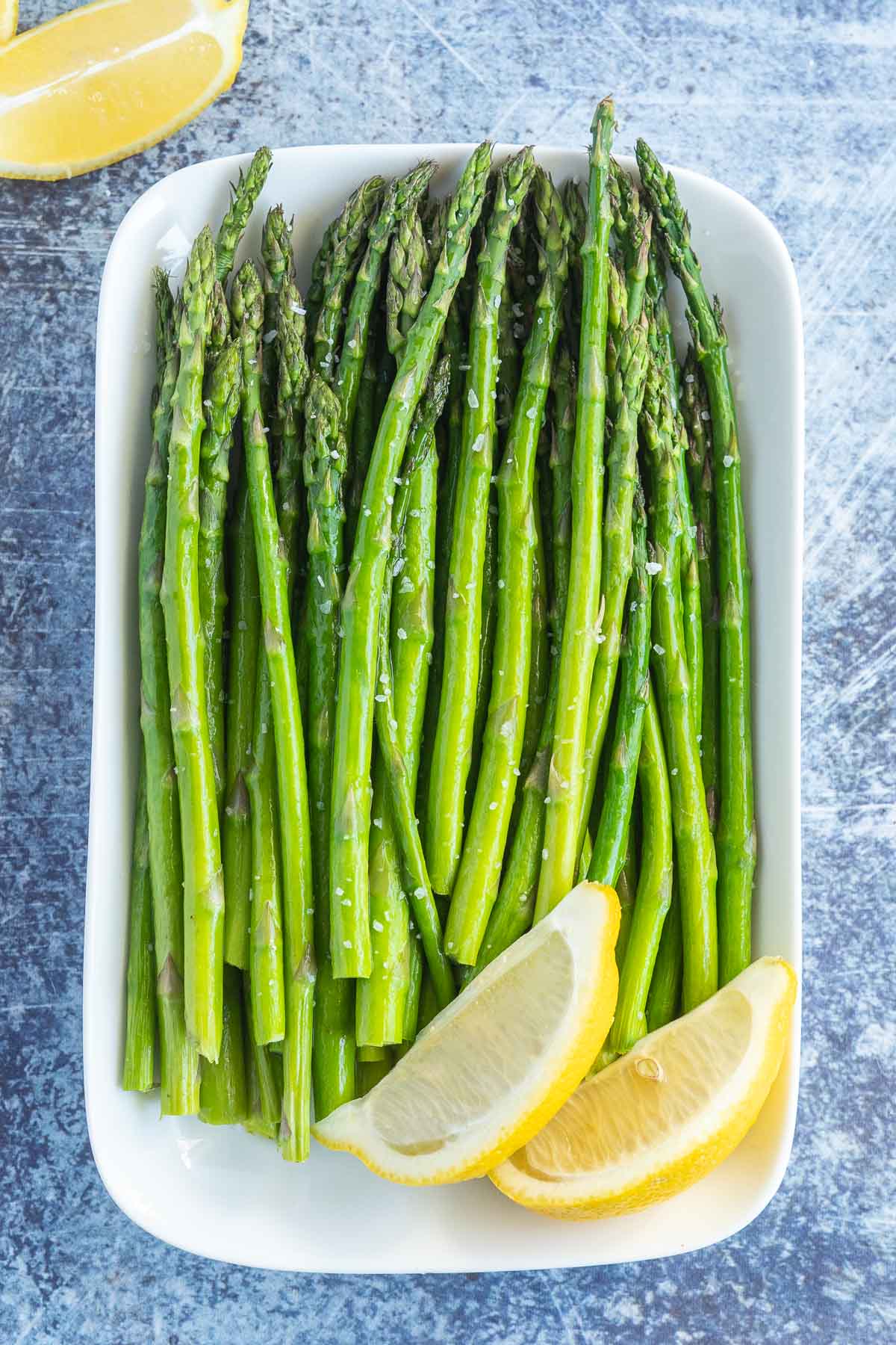 Asparagus on a plate with lemon wedges. 