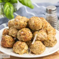 Turkey meatballs on a plate garnished with shredded parmesan cheese.