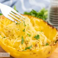 Shredded spaghetti squash in a squash rind scooped with a fork.