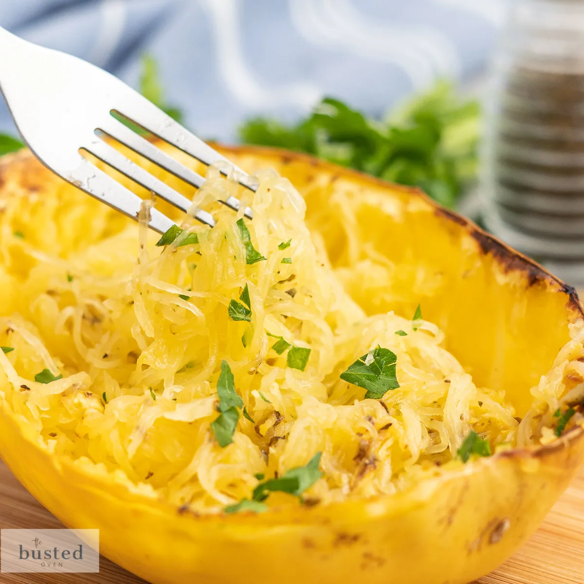 Shredded spaghetti squash in a squash rind scooped with a fork.
