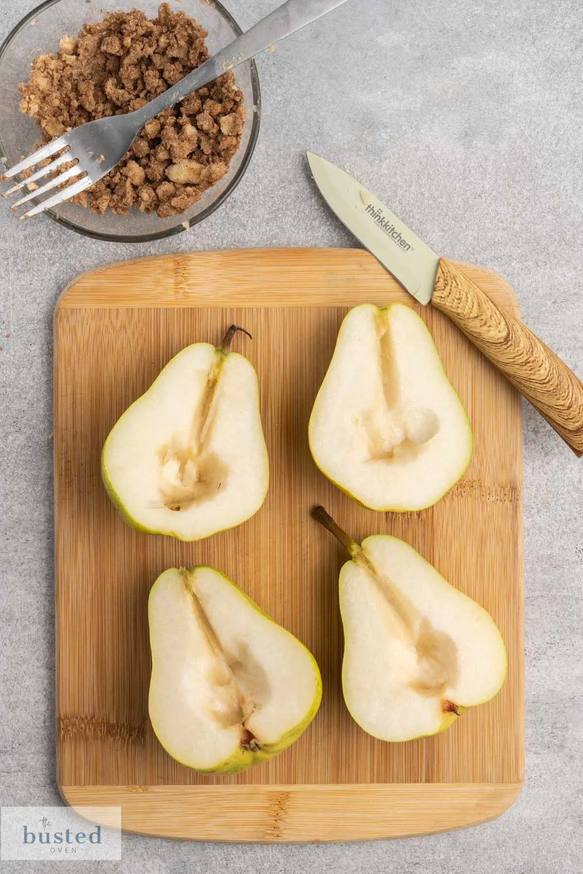 Two pears on a cutting board cut in half with core removed.