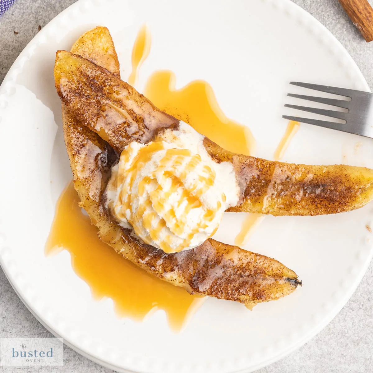 Two banana halves with melted brown sugar, ice cream and caramel sauce.