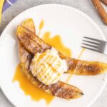 Two banana halves with melted brown sugar, ice cream and caramel sauce.