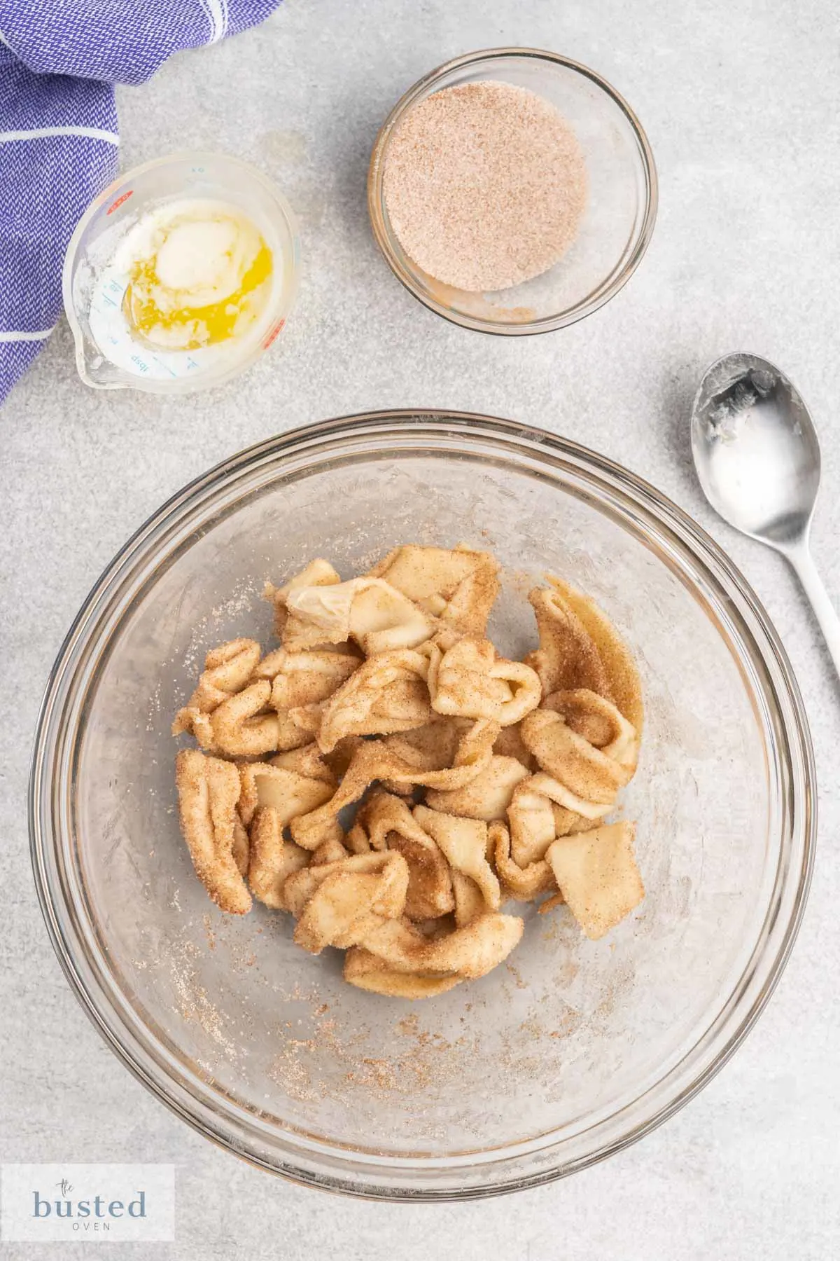 Raw pastry strips in a bowl tossed with brown sugar and cinnamon.