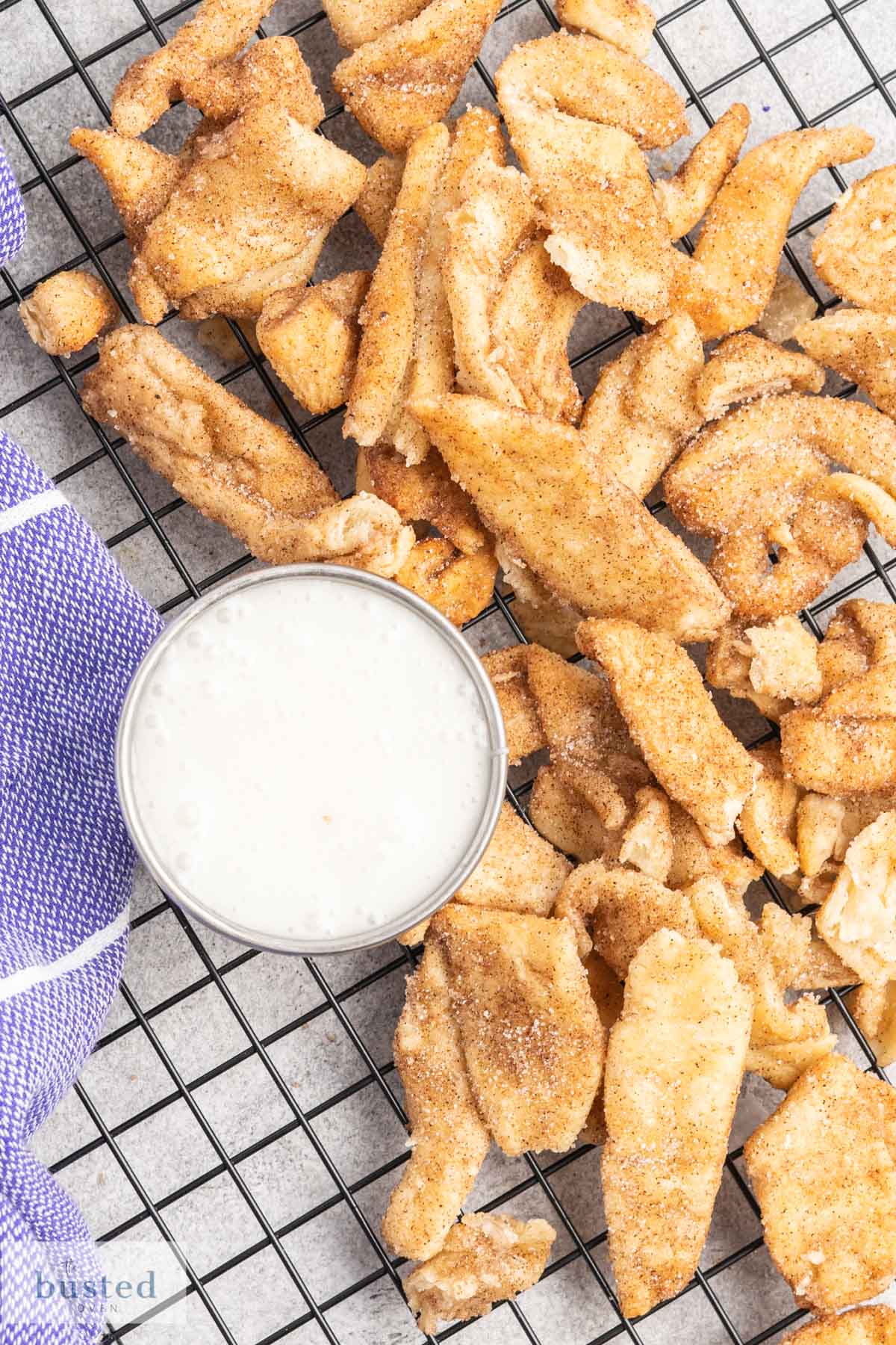 A tray of cinnamon sugar pastry and a dish of icing for dipping. 