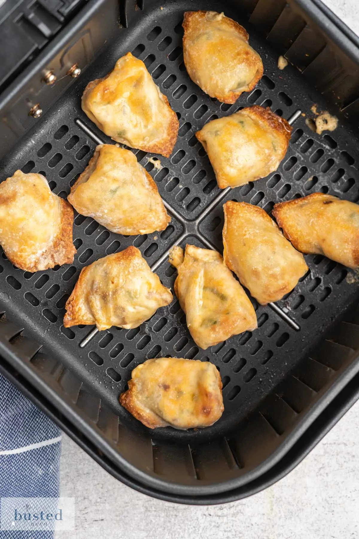 Crispy wontons in an air fryer basket.